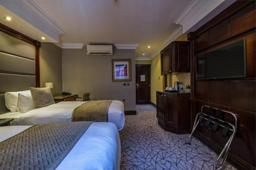 ein Hotelzimmer mit 2 Betten und einem Flachbild-TV in der Unterkunft Hyde Park International in London