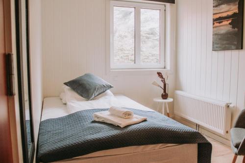 a small bedroom with a bed with a towel on it at Røvær Havhotell in Røvær