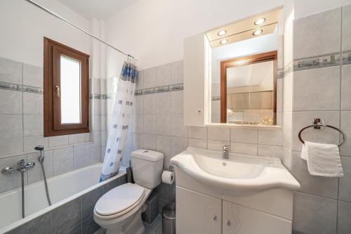 een badkamer met een wastafel, een toilet en een spiegel bij Mariel House Fiskardo Kefalonia in Fiskardho