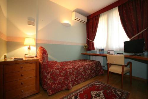 Habitación de hotel con cama, escritorio y TV. en Paradise Hotel & Wellness en Saint Vincent