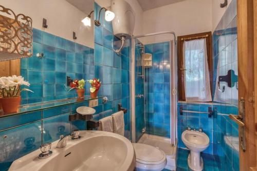 Un baño con azulejos azules, lavabo e inodoro. en Splendida spiaggia di Porto Istana Sconti, en Porto Istana