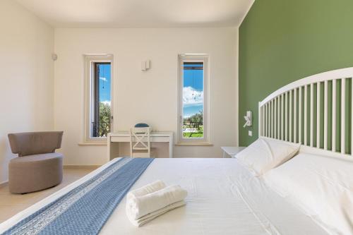 ein Schlafzimmer mit einem großen Bett mit einem Stuhl und Fenstern in der Unterkunft Villa Cesira by Perle di Puglia in Muro Leccese