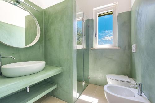 ein grünes Bad mit einem Waschbecken und einem Spiegel in der Unterkunft Villa Cesira by Perle di Puglia in Muro Leccese