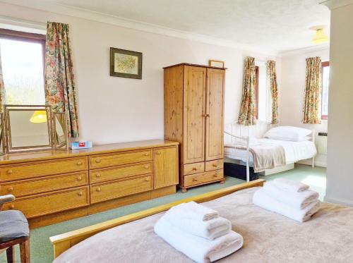 Bramley Cottage في Charlton: غرفة نوم بسريرين وخزانة ومرآة