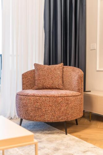a chair sitting in a living room next to a curtain at Luxury 3BDR In The Heart Of Jerusalem in Jerusalem