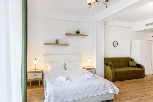 a white bedroom with a bed and a couch at Clabucet Alpin Studio in Predeal
