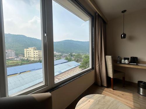 a room with a large window with a view of a roof at Sachika Hotels, Guwahati in Guwahati