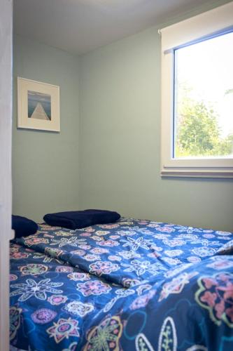 a bed with a blue comforter and a window at Bungalow mit Wintergarten in Seehof