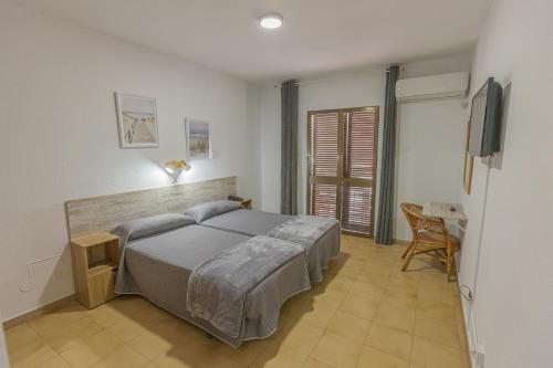コニル・デ・ラ・フロンテーラにあるHotel Tres Jotas Conilのベッドルーム1室(ベッド1台、テーブル、椅子付)