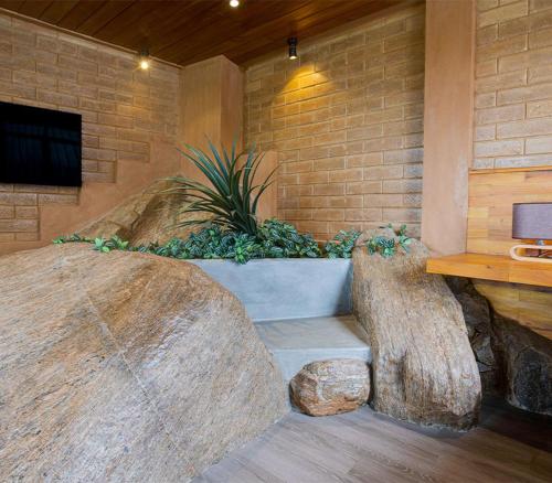 a bench in a room with a stone wall at Waterfall Villa by Opulence in Talawakele