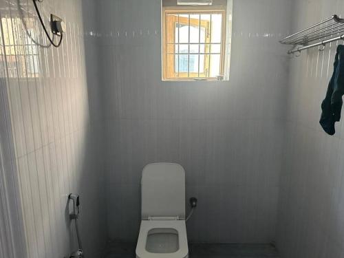 La salle de bains est pourvue de toilettes blanches et d'une fenêtre. dans l'établissement Stunning 4-Bedroom Family Haven, à Patna