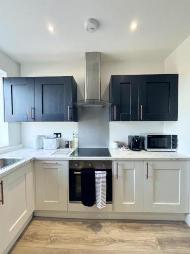 a kitchen with white cabinets and a stove top oven at Luxury Norwich City Centre Flat - Free Parking in Norwich