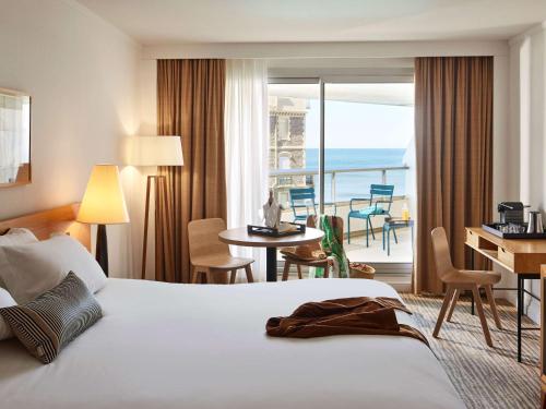 ビアリッツにあるソフィテル ビアリッツ レ ミラマー タラッサのベッド付きのホテルルームで、海の景色を望めます。