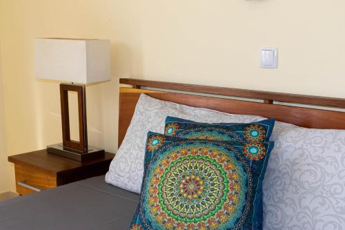 a bed with a pillow and a table with a lamp at Beauty Plaza Suites in Santa Maria