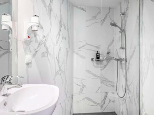 een witte badkamer met een douche en een wastafel bij ibis Styles Amsterdam Amstel in Amsterdam
