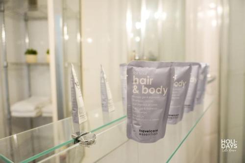 une rangée de produits pour les cheveux et le corps sur une étagère dans une salle de bain dans l'établissement Brisa Marina Apartamento, à Empuriabrava