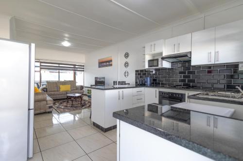 a kitchen with white cabinets and a living room at Safi Luxury Self-Catering Suite 8 in East London
