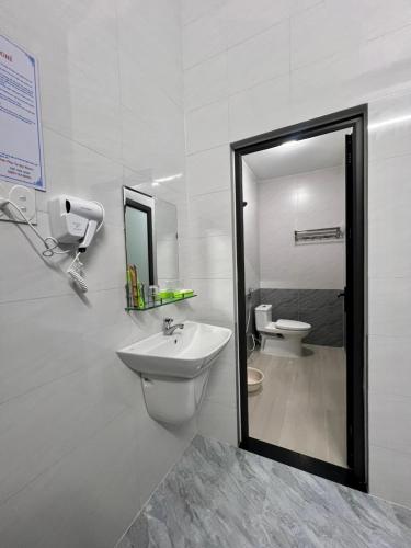 a bathroom with a sink and a mirror and a toilet at Nhà Nghỉ Thiên Tân 2 in Quang Ngai