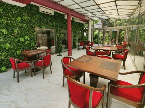 a restaurant with tables and chairs and a green wall at The V Sadan in Mumbai