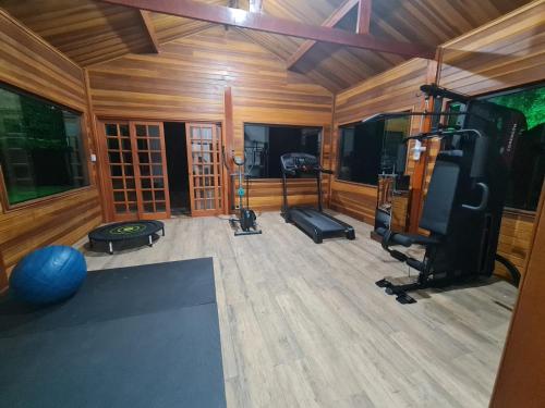 a living room with a gym with a television and a flat screen at Chalé Tucano Recanto Buscapé SFX in São Francisco Xavier