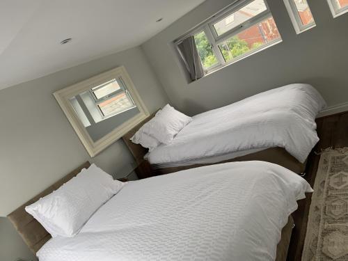 two beds in a room with two windows at Adanhouse-stockland spacious 5 bedroom house sleeps 12 private garden in Cardiff