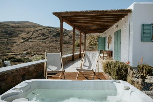 eine Badewanne auf einer Terrasse mit Stühlen und einem Haus in der Unterkunft Aloe Comfort House by KHI in Kythnos