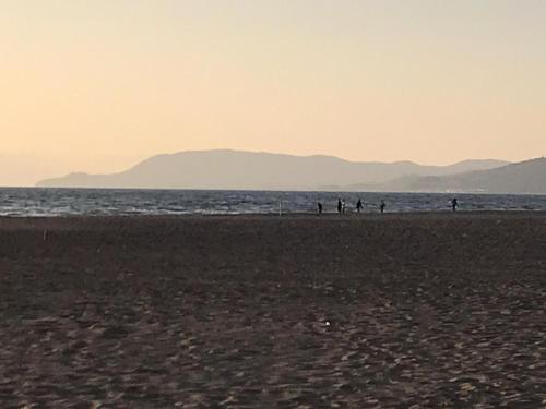 een groep mensen die op het strand lopen bij Residence il Tombolo in Principina a Mare