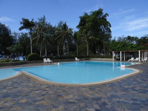 una piscina en un complejo con árboles en el fondo en VIP Condochain Rayong, en Ban Phe