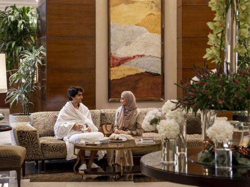 فندق قصر مكة رافلز في مكة المكرمة: يجلس شخصان على أريكة في غرفة المعيشة