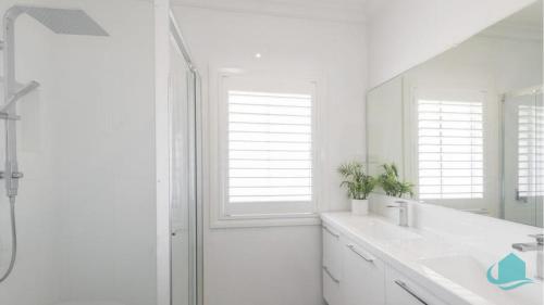 a white bathroom with a sink and a shower at Beachside Oasis in Caves Beach