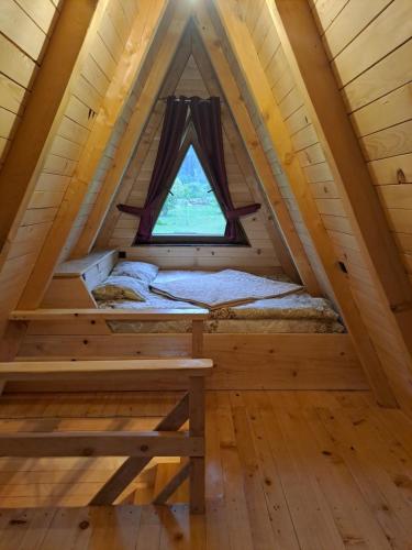 uma cama numa pequena casa com uma janela em Wooden cottages "KONAK" em Šavnik