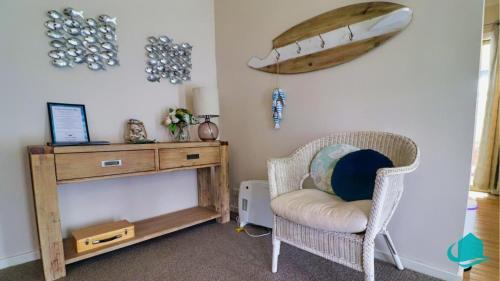 a room with a chair and a table and a surfboard on the wall at Beachside Cottage at Blacksmiths in Blacksmiths