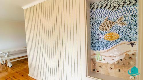 a room with a wall with a painting on it at Coastal Horizons Beach House in Caves Beach