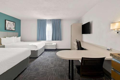 ミッドベールにあるMainStay Suites Salt Lake City Fort Unionのベッド2台とテーブルが備わるホテルルームです。