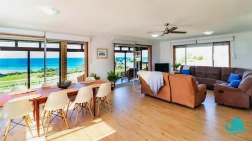 a living room with a couch and a table and chairs at Ripples by the Sea in Caves Beach