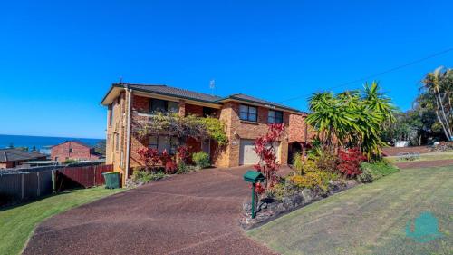a brick house with plants on the side of it at Waves at Caves in Caves Beach