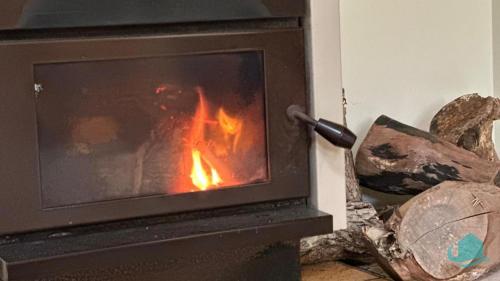 a stove with a fire in a room at Wemberley Lakehouse in Wangi Wangi