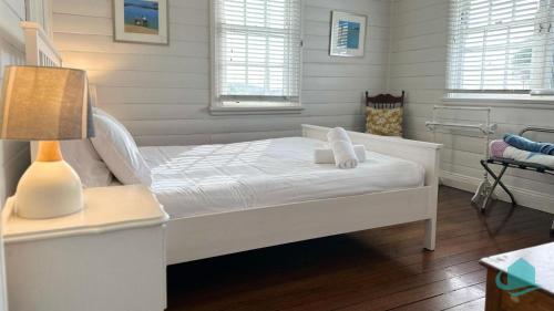sypialnia z białym łóżkiem i lampką w obiekcie By the Beach at Catho w mieście Catherine Hill Bay