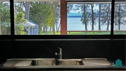 Bonnells BayにあるCasuarina Waters - waterfront home on Lake Macquarieの水辺を望む窓付きのキッチンシンク