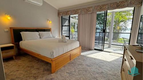 1 dormitorio con cama y ventana grande en Casuarina Waters - waterfront home on Lake Macquarie, en Bonnells Bay