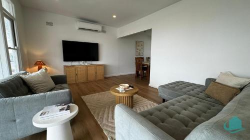 Una sala de estar con dos sofás y un televisor de pantalla plana. en Cove on Caves - Minutes from the Beach, en Caves Beach
