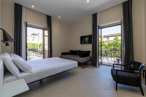 a bedroom with a bed and a couch and windows at Palazzo Albergamo in Favara