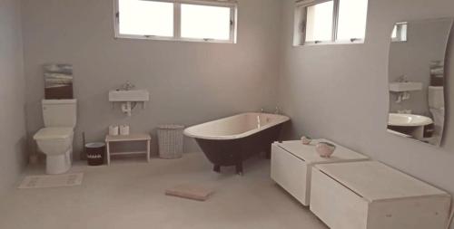 ein Badezimmer mit Badewanne, Toilette und Waschbecken in der Unterkunft Betty's Bay Cottage in Bettyʼs Bay