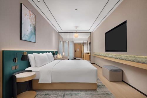 a hotel room with a bed and a flat screen tv at Hilton Garden Inn Chengdu Chunxi Road Center in Chengdu