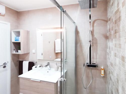 La salle de bains est pourvue d'une douche et d'un lavabo. dans l'établissement Apartment Praia Rocha Vista Mar Sand, à Portimão