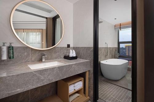uma casa de banho com um lavatório, uma banheira e um espelho. em Hilton Garden Inn Chengdu Chunxi Road Center em Chengdu