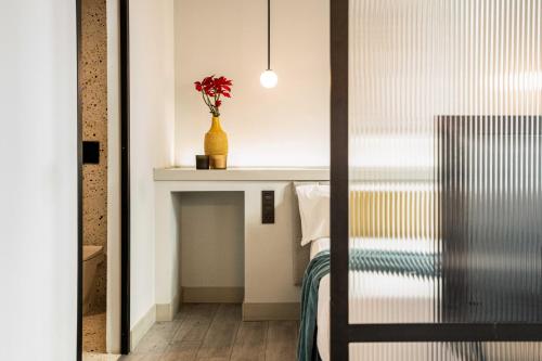 - une chambre avec un lit et un vase avec des fleurs sur une étagère dans l'établissement Coeo Apart-Hotel Parras, à Malaga