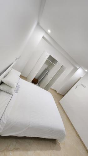 1 cama blanca grande en una habitación blanca en Appartements climatisés JANYA HOLIDAYS, en Alhucemas