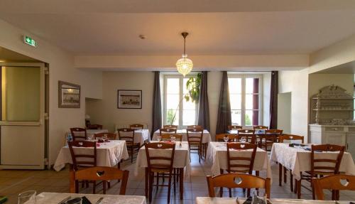 a dining room with tables and chairs and a chandelier at Le Fin Chapon in Excideuil