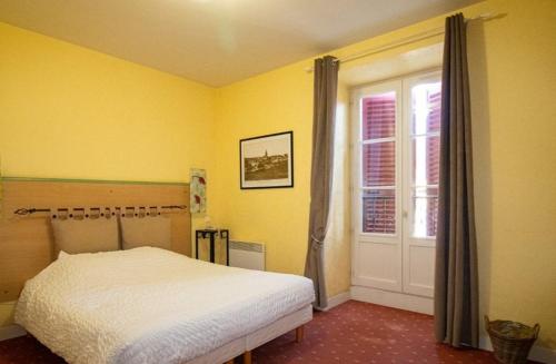 a yellow bedroom with a bed and a window at Le Fin Chapon in Excideuil